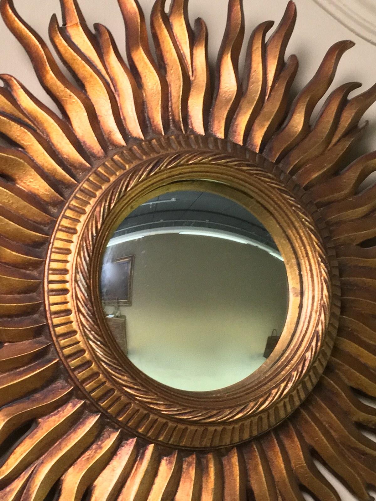 A close view of the sculpted gold rays of a sunburst mirror
