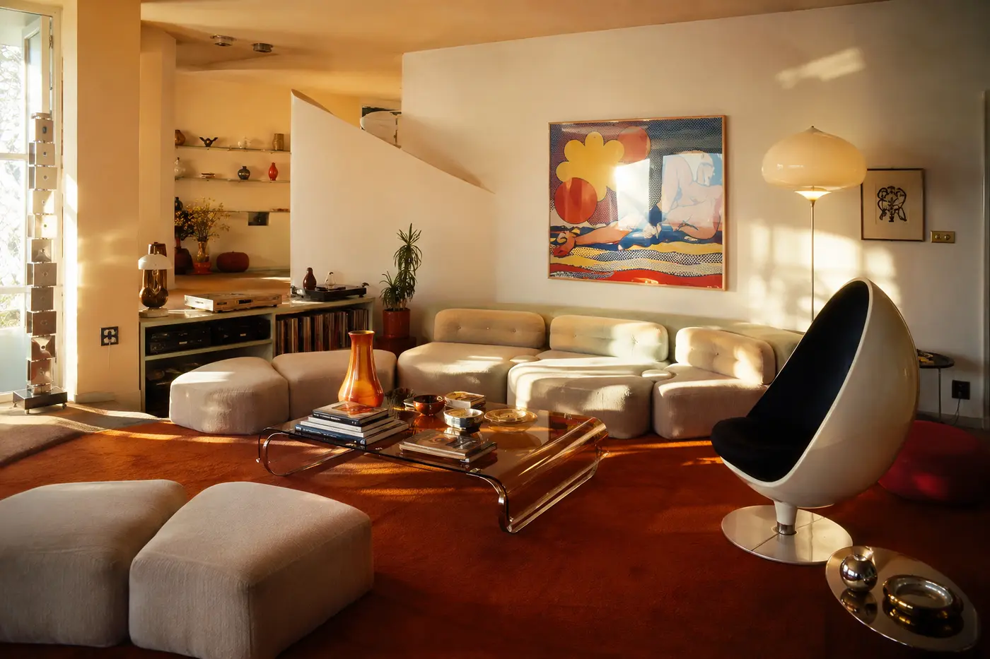 A cream sunken lounge with orange carpet and an egg-shaped chair